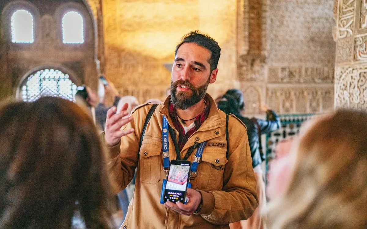 A guide explaining a Nasrid arch to a small group inside the Alhambra